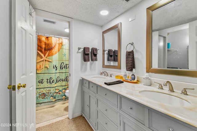 bathroom with a textured ceiling and dual bowl vanity