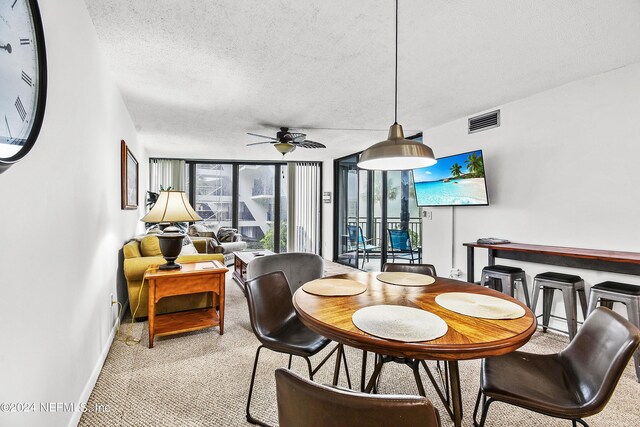 dining area featuring a wall of windows, light carpet, a textured ceiling, and ceiling fan