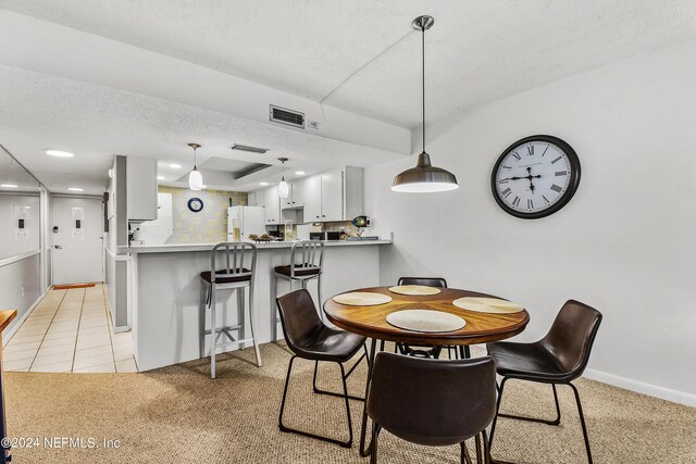 dining space featuring light tile patterned flooring and a textured ceiling