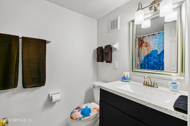 bathroom with toilet, vanity, and a textured ceiling