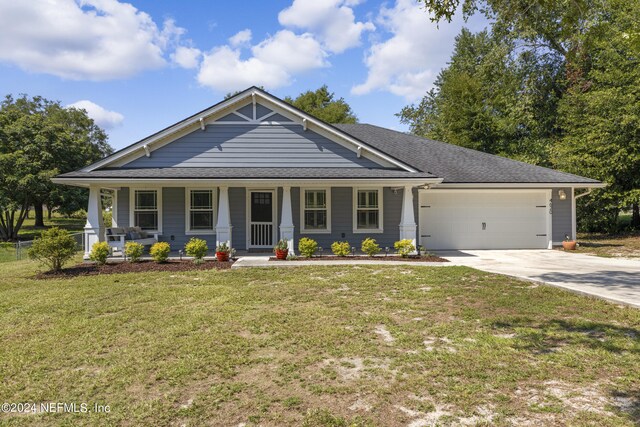 view of front of house with covered porch, a garage, and a front yard