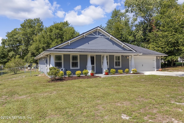 view of front of property featuring a garage, a front lawn, and covered porch