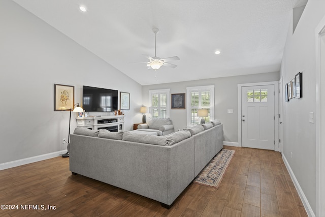 living room with dark wood-type flooring, ceiling fan, and vaulted ceiling