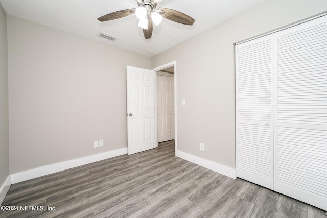 unfurnished bedroom featuring ceiling fan, wood-type flooring, and a closet