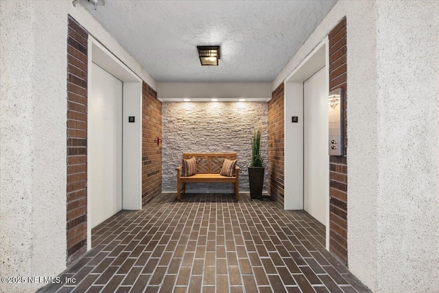 6000 San Jose Blvd Unit 11-C, Jacksonville, FL 32217 - hallway with elevator, a textured ceiling, and brick floor