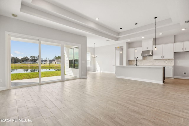 85425 Sandy Ridge Loop Unit 0085, Yulee, FL 32097 - unfurnished living room featuring a water view, a sink, baseboards, light wood-style floors, and a tray ceiling