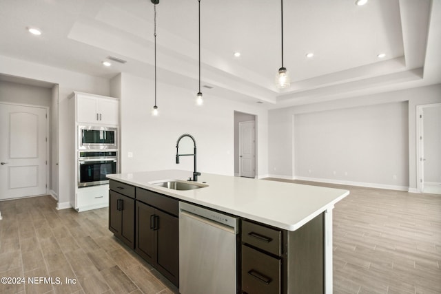 85425 Sandy Ridge Loop Unit 0085, Yulee, FL 32097 - kitchen with a center island with sink, appliances with stainless steel finishes, a tray ceiling, light countertops, and a sink