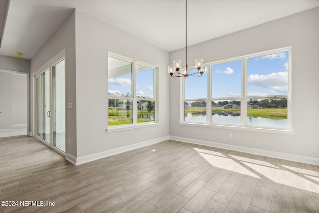 85425 Sandy Ridge Loop Unit 0085, Yulee, FL 32097 - unfurnished dining area with baseboards, a water view, a notable chandelier, and light wood finished floors
