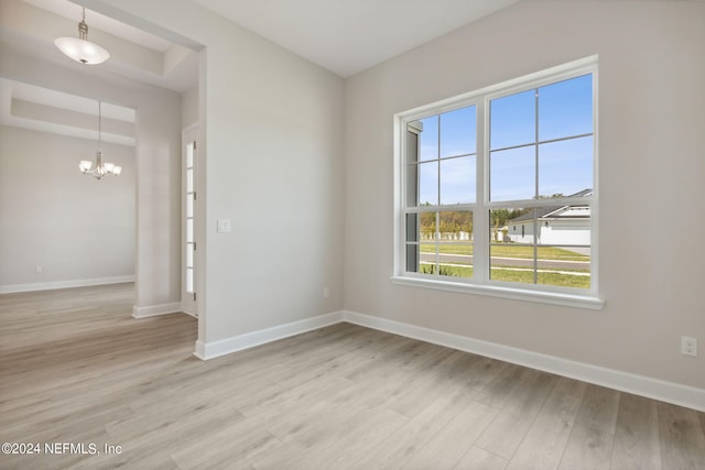 empty room with light hardwood / wood-style flooring and a chandelier