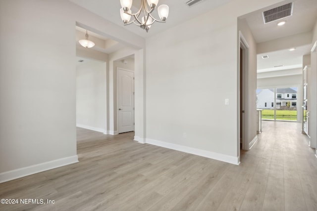 unfurnished room with light wood-type flooring and a chandelier