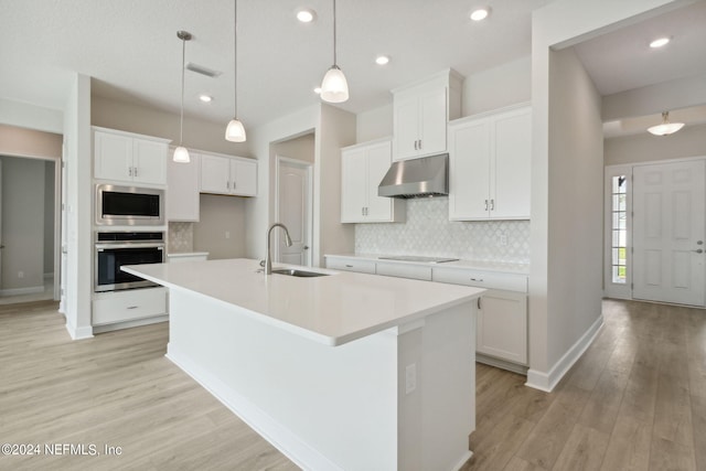 kitchen featuring white cabinets, appliances with stainless steel finishes, a kitchen island with sink, and sink