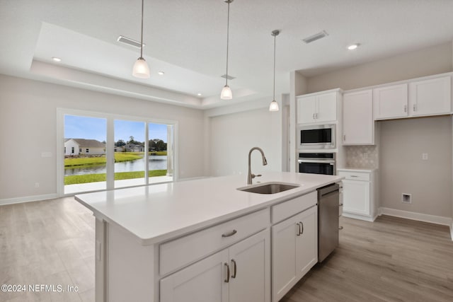 kitchen with pendant lighting, sink, a kitchen island with sink, stainless steel appliances, and a water view