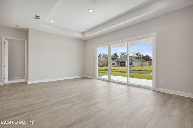 unfurnished room with a tray ceiling and light hardwood / wood-style floors