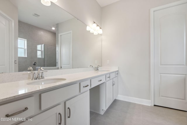 bathroom featuring tiled shower, vanity, and tile patterned flooring