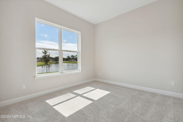 carpeted empty room featuring a water view