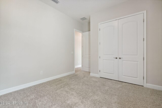 unfurnished bedroom featuring light colored carpet and a closet