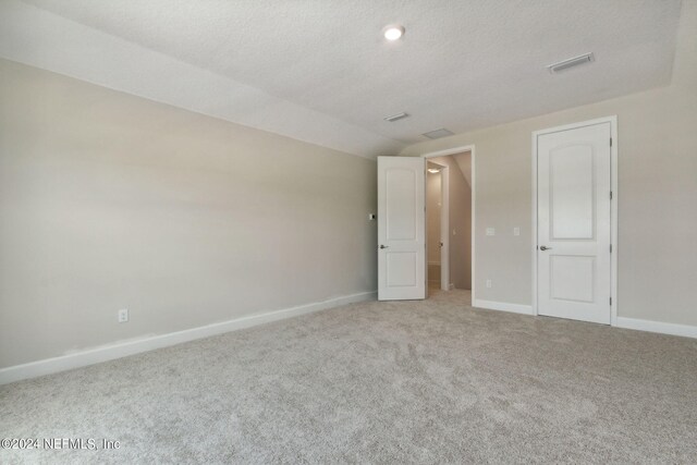 unfurnished bedroom featuring a textured ceiling and light colored carpet