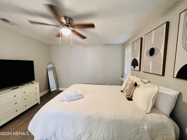 bedroom featuring dark wood-type flooring, ceiling fan, and a textured ceiling