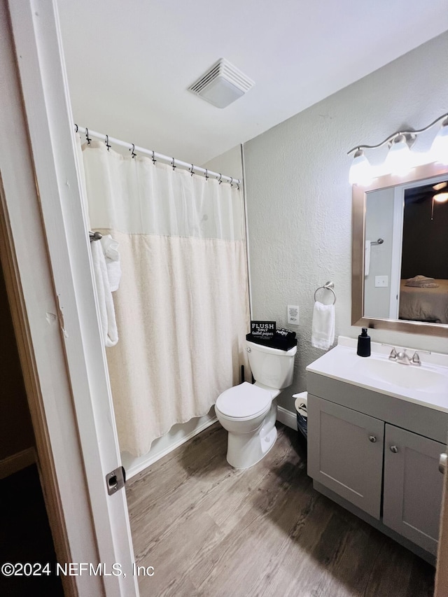 full bathroom with vanity, hardwood / wood-style floors, shower / bath combo, and toilet