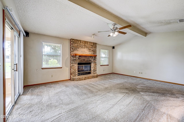 unfurnished living room with light carpet, lofted ceiling with beams, a brick fireplace, ceiling fan, and a textured ceiling