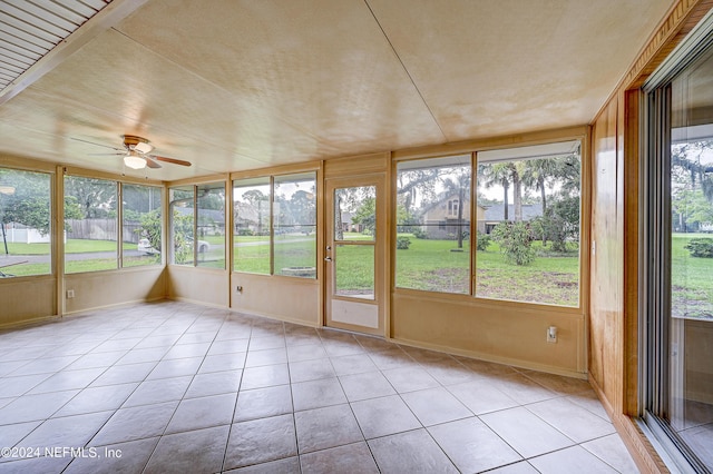 unfurnished sunroom featuring ceiling fan and a healthy amount of sunlight