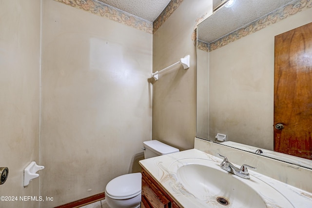 bathroom featuring a textured ceiling, vanity, and toilet