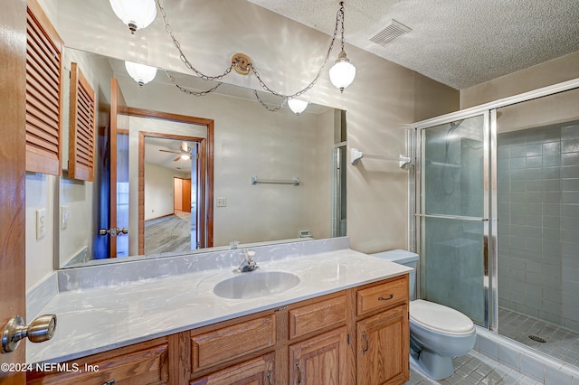 bathroom with vanity, a textured ceiling, a shower with door, ceiling fan, and toilet