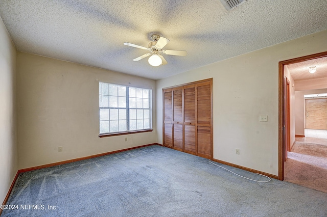 unfurnished bedroom featuring carpet, a textured ceiling, a closet, and ceiling fan