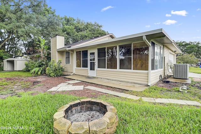 rear view of house featuring a fire pit, a storage shed, and central air condition unit