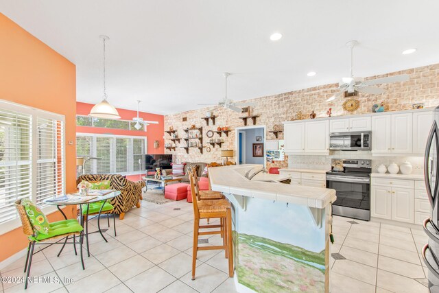 kitchen featuring white cabinets, ceiling fan, stainless steel appliances, a kitchen breakfast bar, and tile countertops