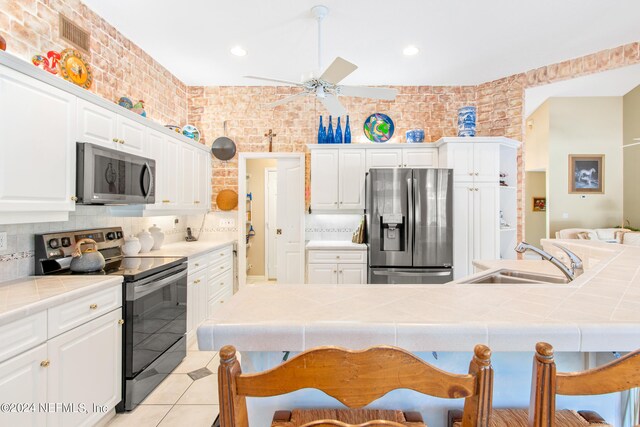 kitchen featuring backsplash, ceiling fan, stainless steel appliances, tile countertops, and sink