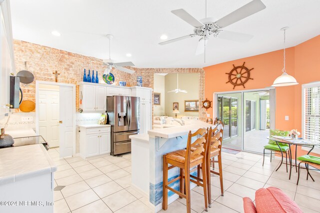 kitchen with stainless steel fridge, brick wall, a wealth of natural light, and ceiling fan