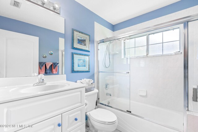 full bathroom with toilet, vanity, and enclosed tub / shower combo