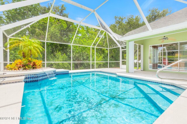 view of swimming pool with pool water feature, ceiling fan, and glass enclosure