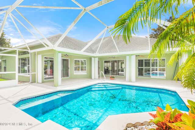 view of pool with a patio, ceiling fan, and glass enclosure