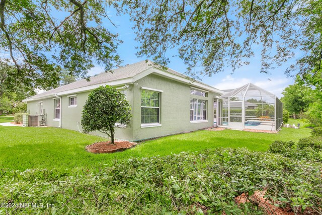 view of property exterior featuring a lawn and glass enclosure