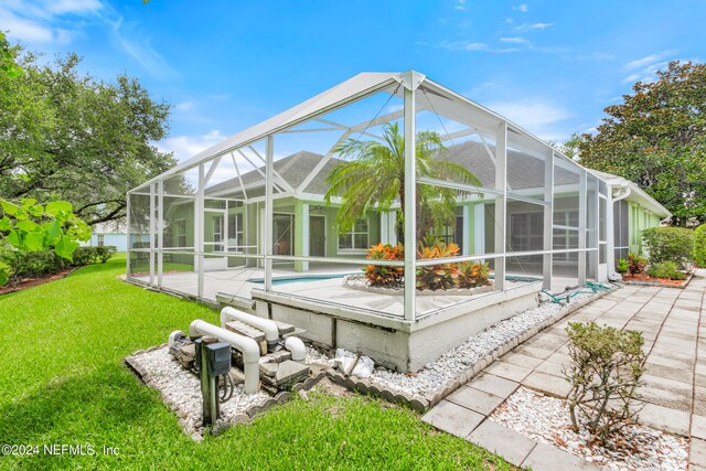 back of house featuring a patio, a lawn, and a lanai