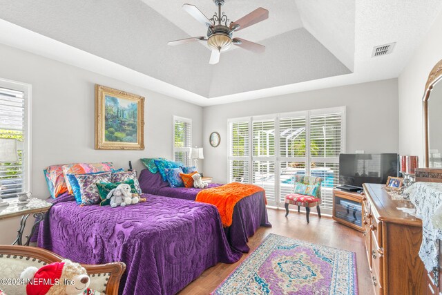 bedroom featuring ceiling fan, light hardwood / wood-style flooring, and a tray ceiling