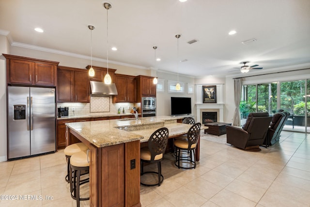 kitchen with a large island with sink, ceiling fan, decorative light fixtures, a kitchen bar, and stainless steel appliances