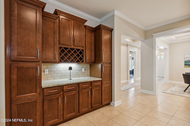 bar featuring decorative backsplash, light tile patterned floors, light stone counters, and ornamental molding