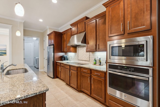 kitchen with appliances with stainless steel finishes, sink, decorative light fixtures, washer / dryer, and range hood