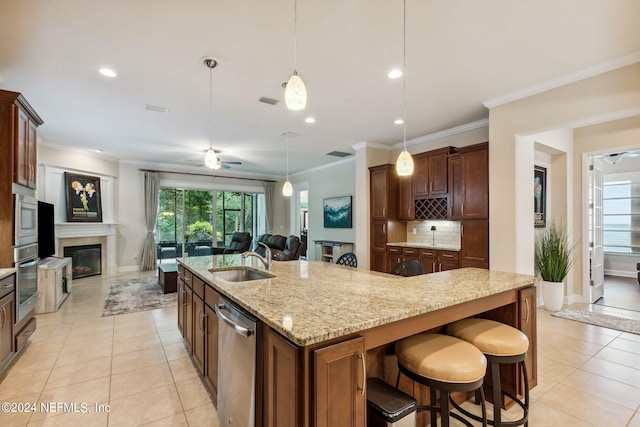 kitchen with ceiling fan, sink, an island with sink, a breakfast bar, and appliances with stainless steel finishes