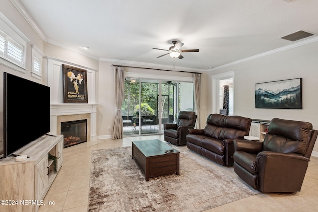 living room featuring ceiling fan, a fireplace, light tile patterned floors, and ornamental molding