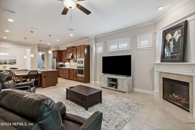 tiled living room with ceiling fan, sink, ornamental molding, and a fireplace