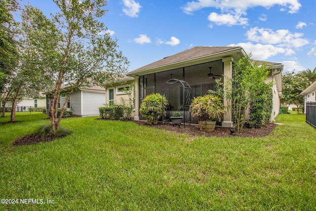 rear view of property with ceiling fan, a lawn, and a sunroom