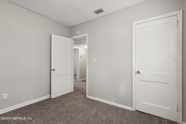 unfurnished bedroom featuring dark carpet and a textured ceiling