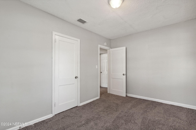 unfurnished bedroom with dark colored carpet and a textured ceiling