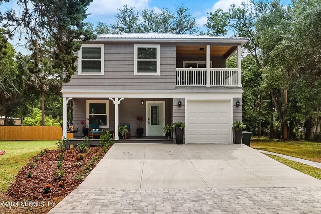 view of front of house with covered porch, a balcony, a garage, and a front lawn