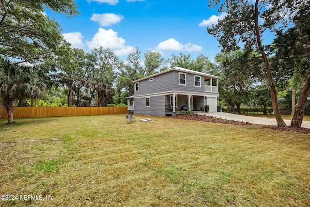 back of property featuring driveway, an attached garage, fence, and a yard