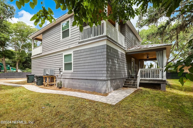 view of property exterior with a yard, a balcony, and ceiling fan